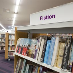 Fiction books section in a library with a shelf of books