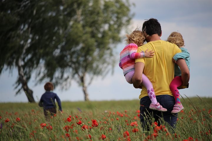 Dad and 3 kids walking in a field